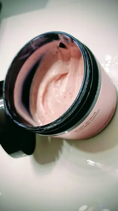 Ανοιχτό βάζο με ροζ κρεμώδες Cotton Candy Body Scrub που περιέχει μικρούς κόκκους.