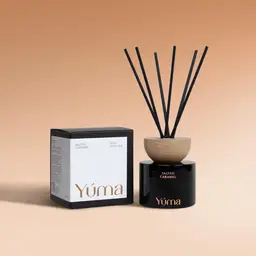 Μαύρο γυάλινο reed diffuser Salted Caramel της YUMA με ξύλινο καπάκι δίπλα στη συσκευασία του.