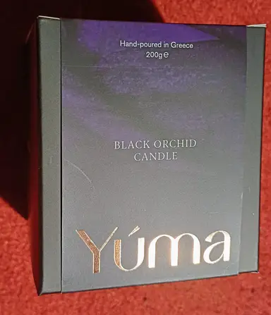 Μαύρο κουτί για το Black Orchid CANDLE της YUMA με χρυσό λογότυπο και μωβ λεπτομέρειες.