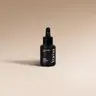 Μαύρο γυάλινο μπουκάλι Salted Caramel της YUMA με σταγονόμετρο σε μπεζ φόντο.