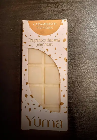 Λευκή μπάρα αρωματικού κεριού Caramelised Popcorn της YUMA σε χάρτινη συσκευασία με χρυσές λεπτομέρειες.