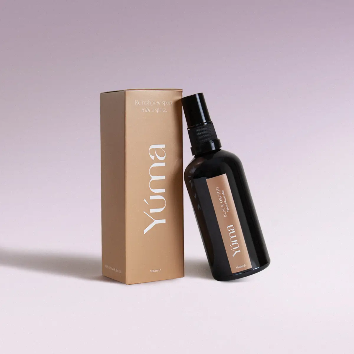 Μαύρο μπουκάλι fabric mist Black Orchid της YUMA δίπλα στην μπεζ χάρτινη συσκευασία του.