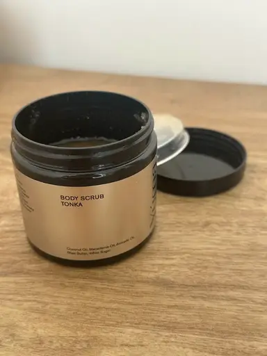 Ανοιχτό βαζάκι Body Scrub Tonka της YUMA με χρυσή ετικέτα πάνω σε ξύλινη επιφάνεια.