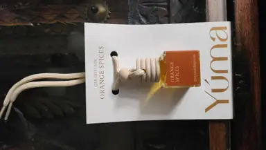 Αρωματικό αυτοκινήτου Orange Spices της YUMA σε γυάλινο μπουκαλάκι με ξύλινο πώμα και κορδόνι.