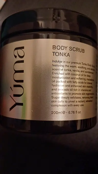 Μαύρο βάζο Body Scrub TONKA της YUMA με ασημί ετικέτα και μαύρα γράμματα σε σκούρο φόντο.