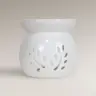 Λευκός κεραμικός καυστήρας για wax melts με διάτρητο σχέδιο φύλλων σε ανοιχτόχρωμο φόντο.