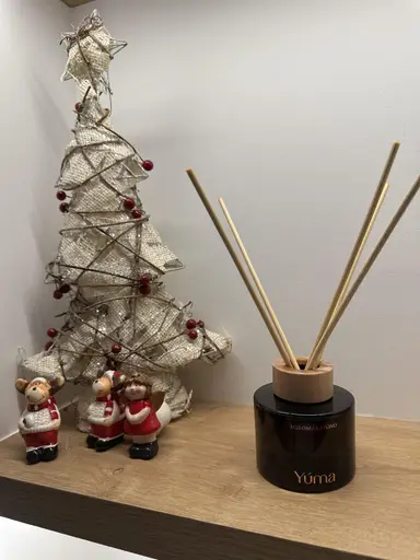 Reed diffuser της YUMA σε άρωμα Melomakarono δίπλα σε διακοσμητικό χριστουγεννιάτικο δέντρο και μικρές φιγούρες.