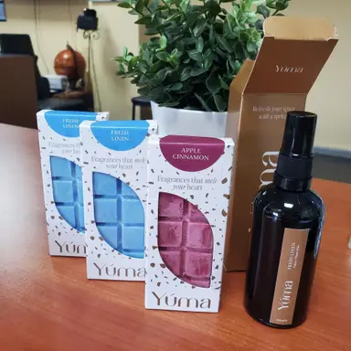 Τρία wax melts της YUMA σε αρώματα Fresh Linen και Apple Cinnamon δίπλα σε ένα room spray.