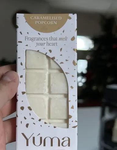 Λευκή μπάρα αρωματικού κεριού Caramelised Popcorn της YUMA σε χάρτινη συσκευασία με χρυσές λεπτομέρειες.