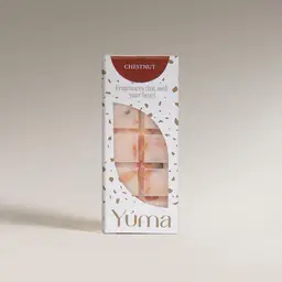 Λευκή συσκευασία YUMA για wax melts Chestnut με άνοιγμα που αποκαλύπτει την ανάγλυφη μπάρα κεριού.
