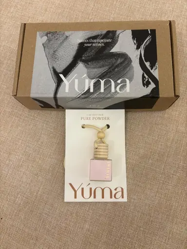 Αρωματικό αυτοκινήτου Pure Powder της YUMA μπροστά από κουτί συσκευασίας.