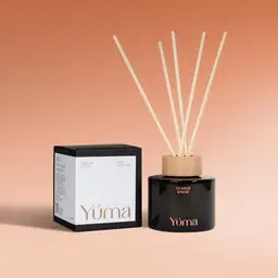 Reed diffuser Orange Spices της YUMA σε σκούρο γυάλινο μπουκάλι δίπλα στη συσκευασία του.