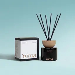 Reed diffuser Laundry Nostalgia της YUMA σε μαύρο γυάλινο δοχείο δίπλα στη χάρτινη συσκευασία του.