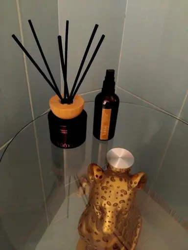 Reed diffuser με μαύρα στικ, αρωματικό σπρέι χώρου και χρυσό διακοσμητικό λεοπάρδαλη πάνω σε γυάλινο τραπέζι.