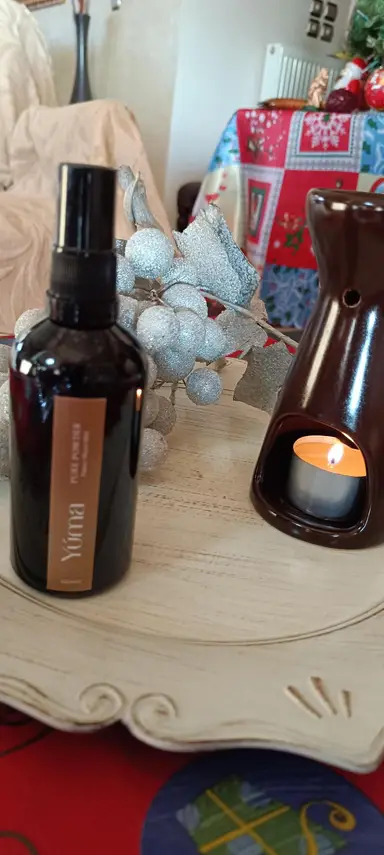 Σκούρο μπουκάλι room spray YUMA Pure Powder δίπλα σε καυστήρα με αναμμένο ρεσό.