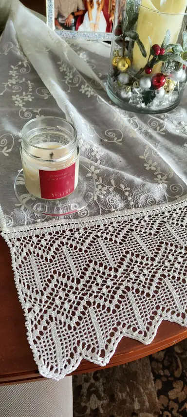 Αρωματικό κερί YUMA σε γυάλινο βαζάκι πάνω σε λευκό δαντελωτό τραπεζομάντηλο με χριστουγεννιάτικη διακόσμηση.