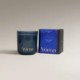 Μπλε γυάλινο κερί Fresh Linen της YUMA δίπλα στη χάρτινη συσκευασία του.