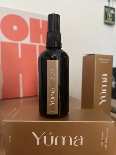 Ένα σκουρόχρωμο μπουκάλι room spray Pine Tree της YUMA πάνω σε καφέ χάρτινη συσκευασία.
