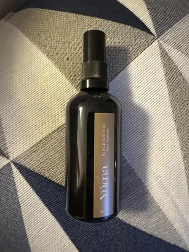 Μαύρο μπουκάλι room spray YUMA Black Orchid πάνω σε ύφασμα με γεωμετρικά σχέδια.