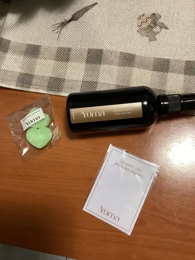 Ένα Fresh Linen room mist της YUMA δίπλα σε πράσινα wax melts σε σχήμα καρδιάς.