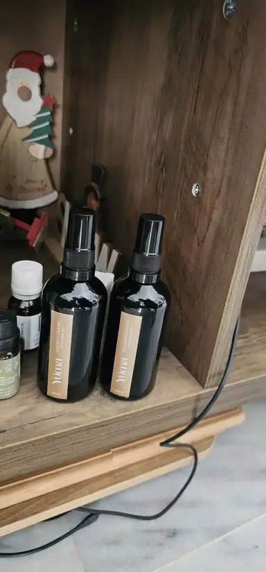 Δύο μαύρα μπουκάλια room spray της YUMA με αρώματα Salted Caramel και Melomakarono σε ξύλινο ράφι.