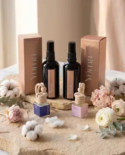 Fresh Linen και Pure Powder Fabric/Room Mist με τα δύο αντίστοιχα Car Diffuser της YUMA ανάμεσα σε άνθη.