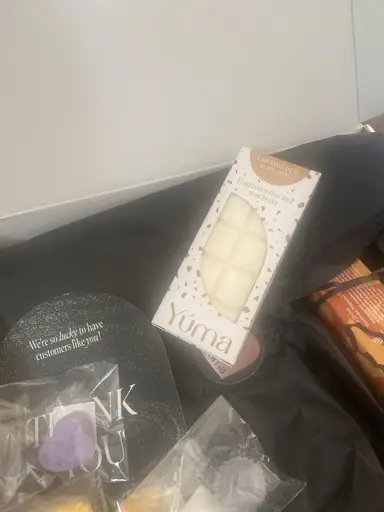 Λευκό wax melt Caramelised Popcorn της YUMA μέσα σε κουτί με μαύρο χαρτί αφής και ευχαριστήρια κάρτα.