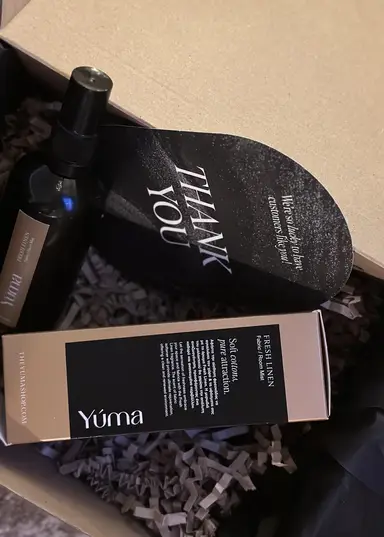 Ένα μπουκάλι σπρέι και η συσκευασία του Fresh LINEN της YUMA μέσα σε κουτί.