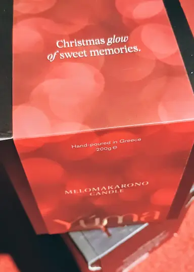 Κόκκινο κουτί για το MELOMAKARONO CANDLE της YUMA με εφέ bokeh και λευκά γράμματα.