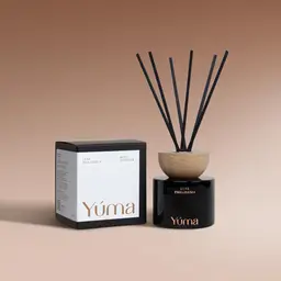 Reed diffuser Luxe Philoxenia της YUMA σε μαύρο γυάλινο δοχείο δίπλα στη συσκευασία του.