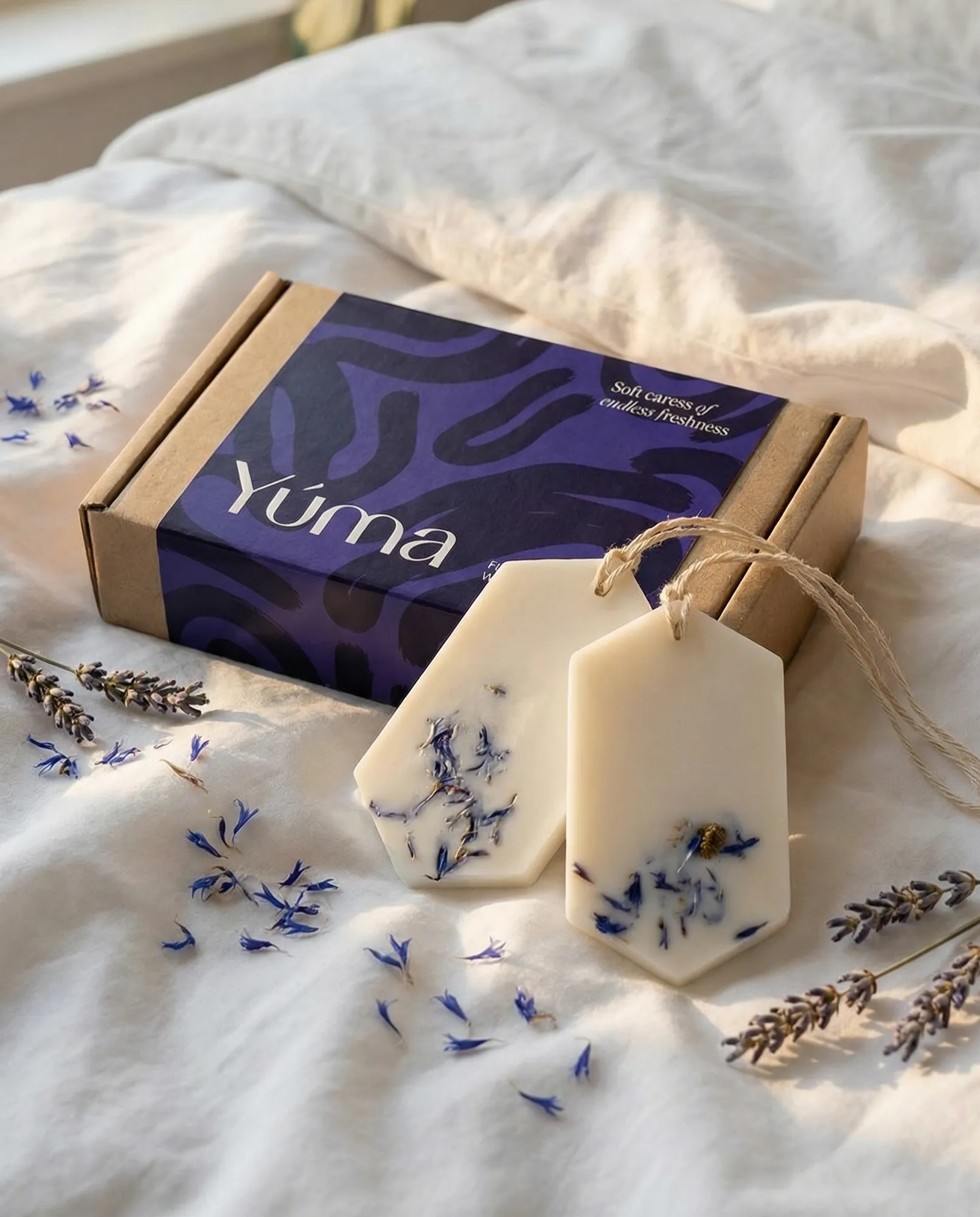 Δύο λευκά Fresh Linen Wax Tablets με αποξηραμένα άνθη πάνω σε λευκά κλινοσκεπάσματα.