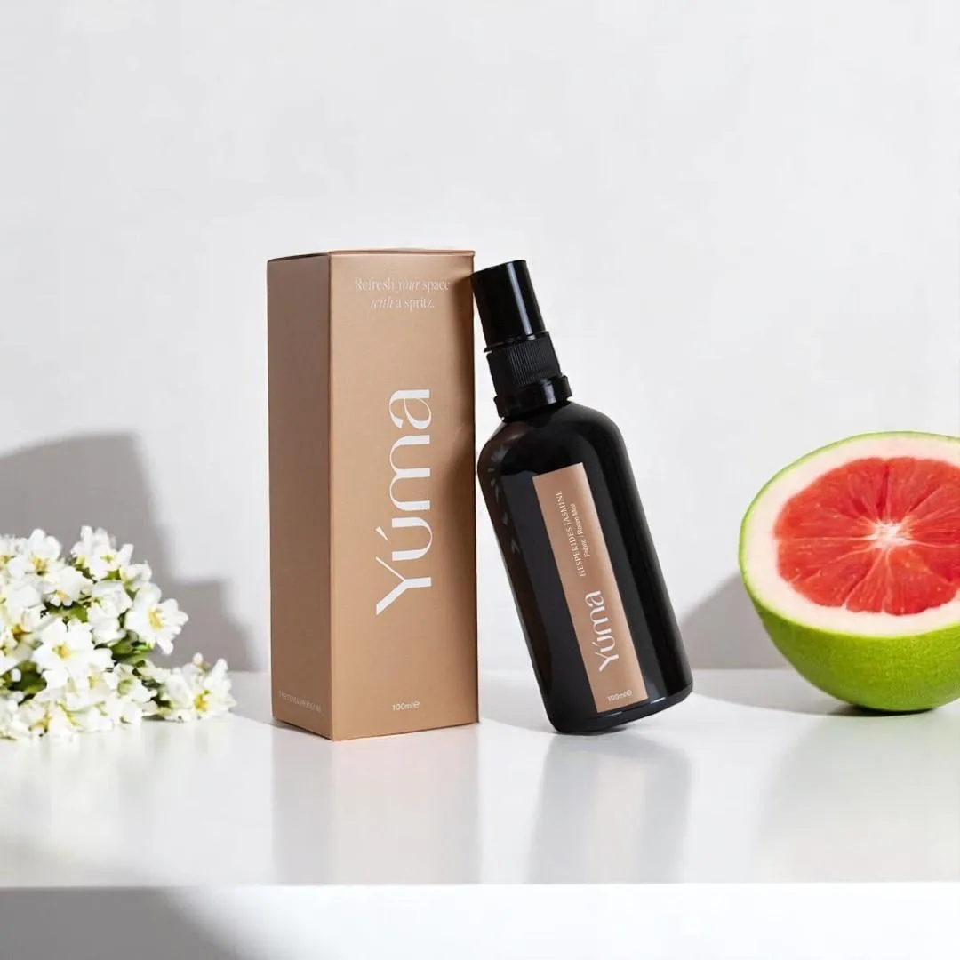 Room spray Hesperides Jasmine της YUMA δίπλα στη συσκευασία του, λευκά άνθη και μισό γκρέιπφρουτ.