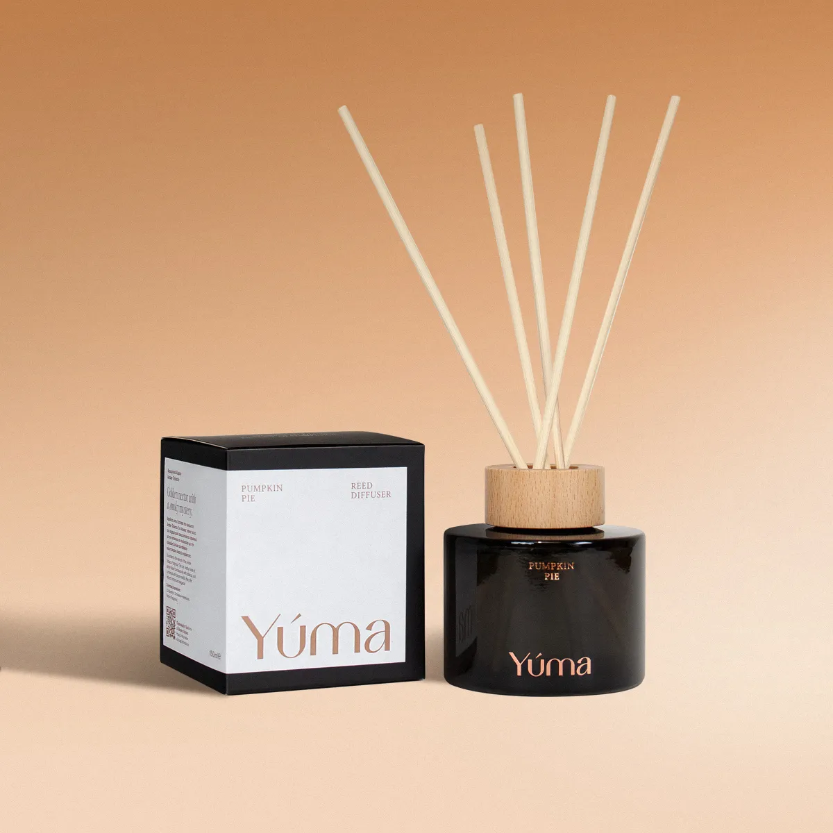Reed diffuser Pumpkin Pie της YUMA σε σκούρο γυάλινο μπουκάλι δίπλα στη χάρτινη συσκευασία του.