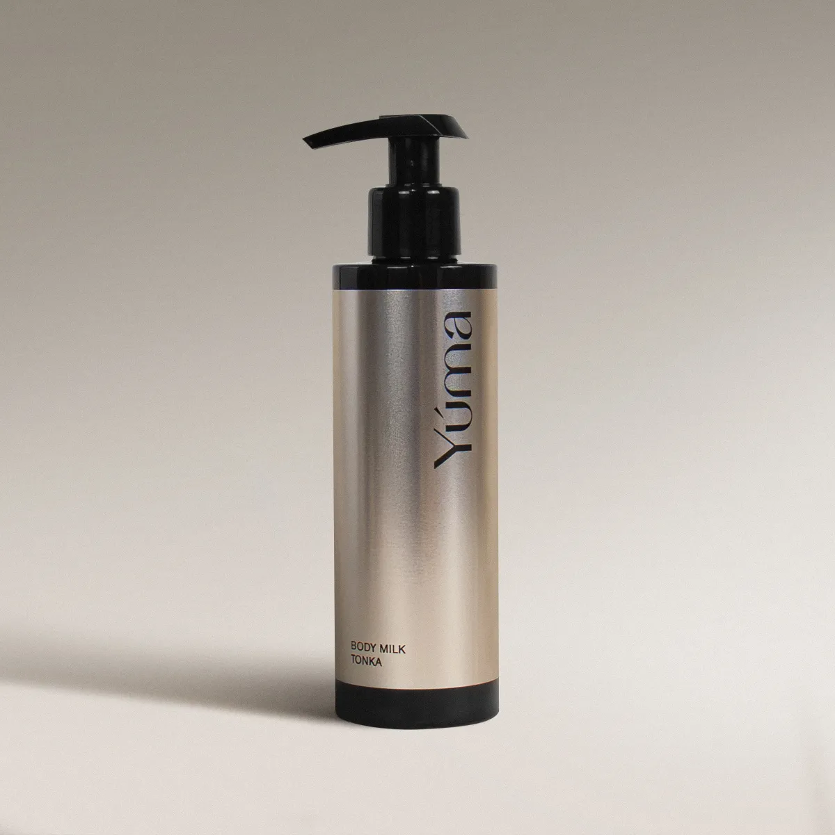Μεταλλικό μπουκάλι Body Milk Tonka της YUMA με μαύρη αντλία σε ουδέτερο φόντο.
