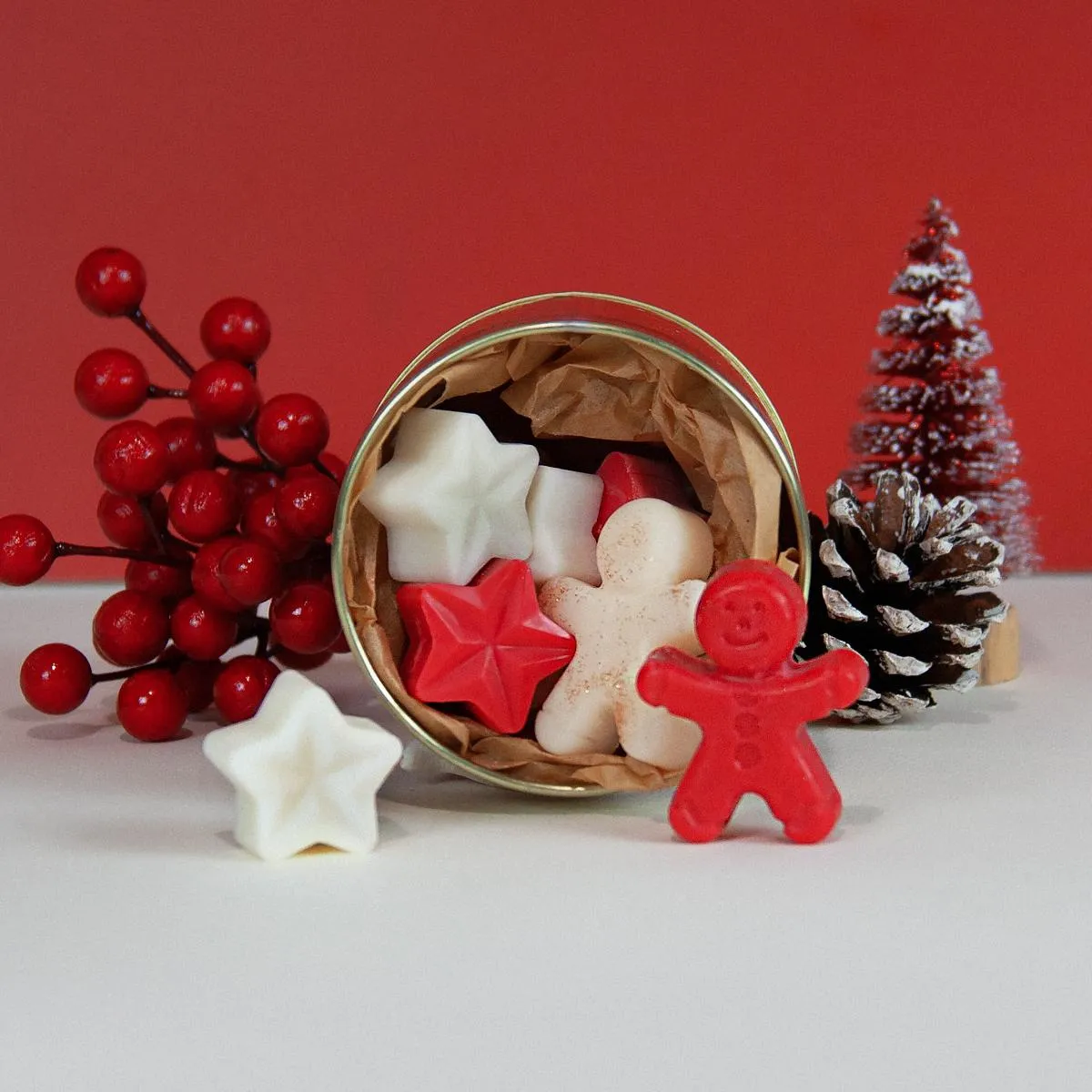 Κόκκινα και λευκά wax melts Melomakarono σε σχήμα αστεριού και ανθρωπάκου μέσα σε μεταλλικό δοχείο.