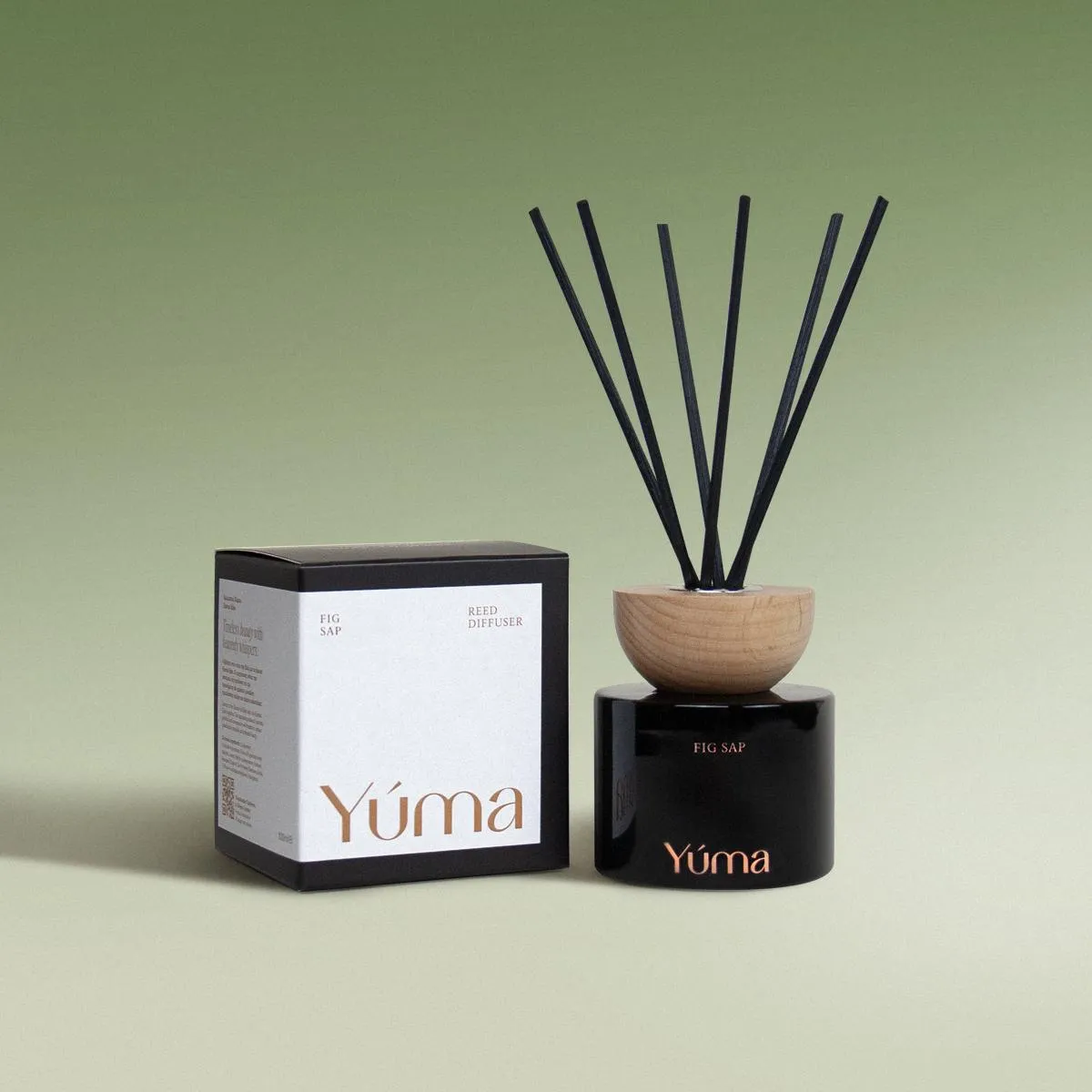 Μαύρο γυάλινο reed diffuser Fig Sap της YUMA με ξύλινο καπάκι δίπλα στη συσκευασία του.