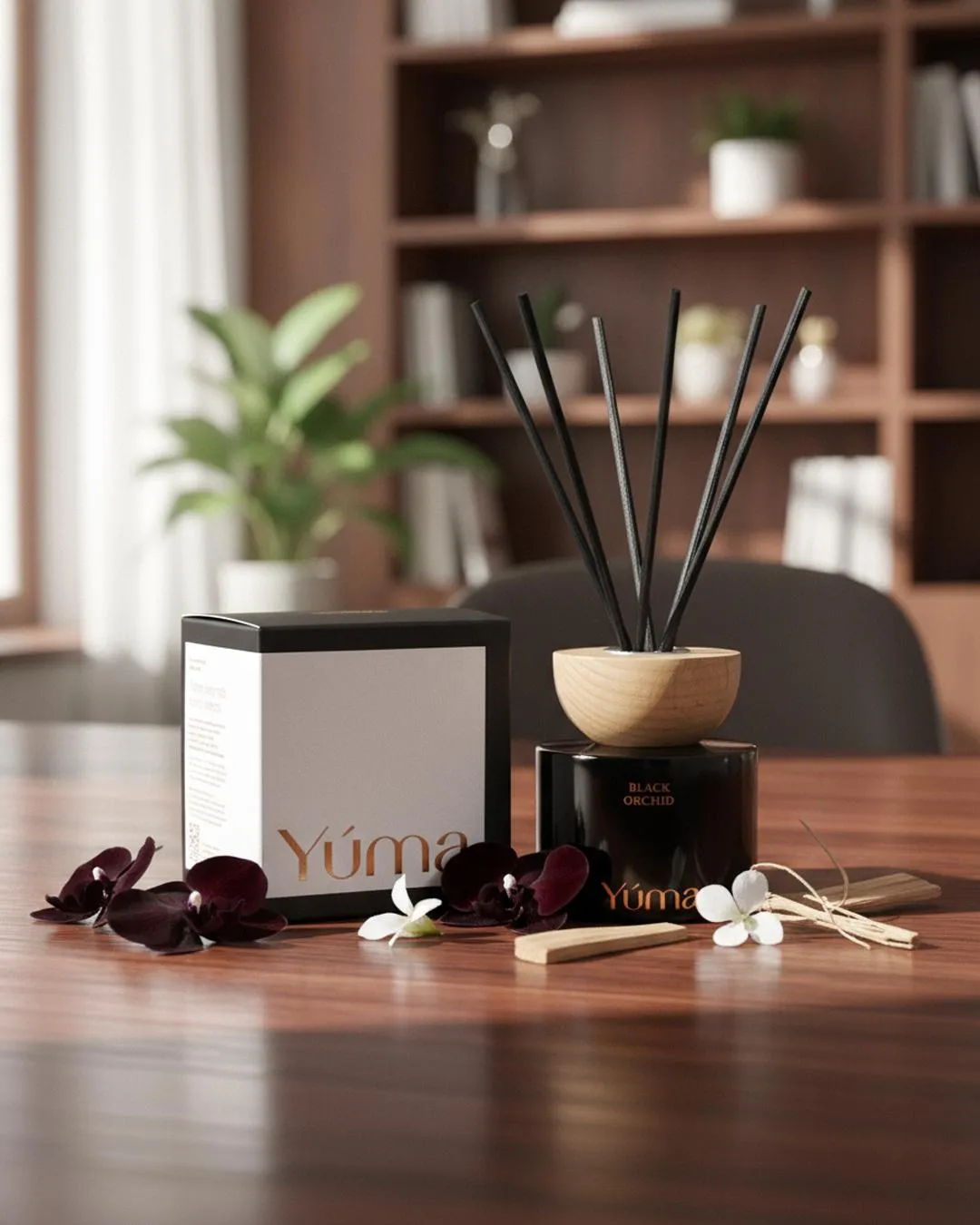 Reed diffuser Black Orchid της YUMA με μαύρα στικ και σκούρα άνθη ορχιδέας σε ξύλινο τραπέζι.