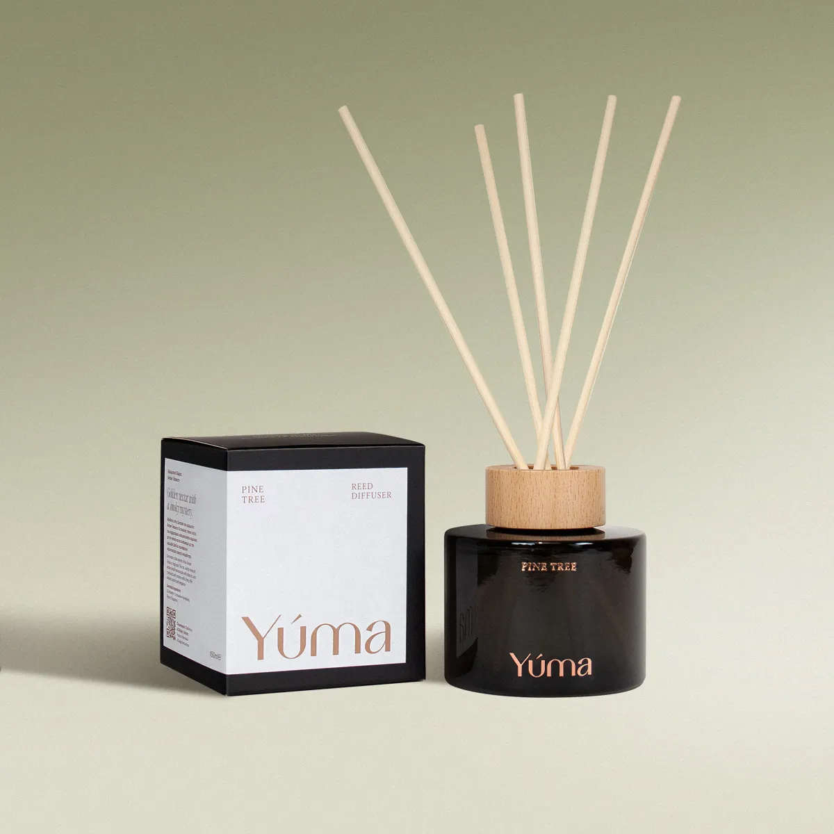 Reed diffuser Pine Tree της YUMA σε σκούρο γυάλινο μπουκάλι δίπλα στη χάρτινη συσκευασία του.