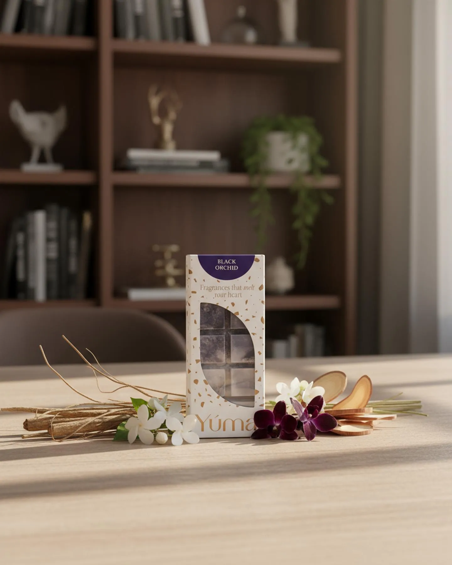 Συσκευασία wax melts Black Orchid της YUMA σε ξύλινο τραπέζι με λευκά και μωβ άνθη.