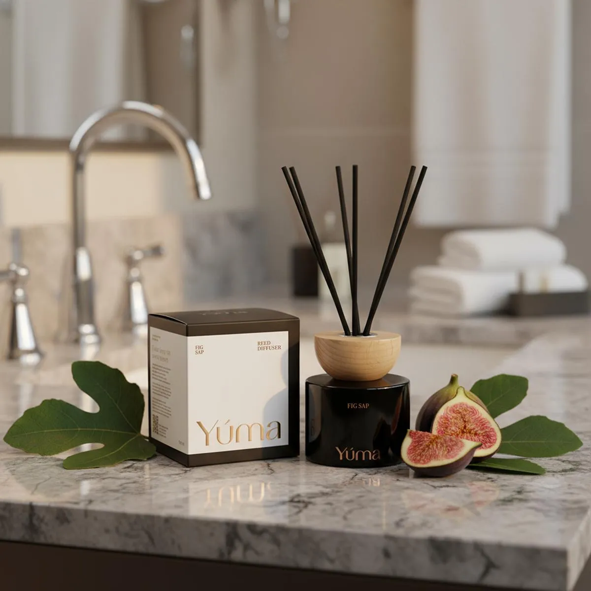 Reed diffuser Fig Sap της YUMA σε μαύρο βάζο δίπλα σε φρέσκα σύκα πάνω σε μάρμαρο.