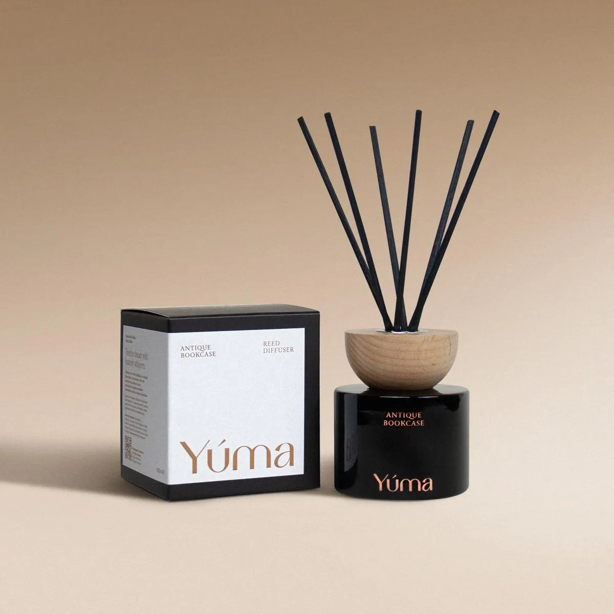 Μαύρο γυάλινο reed diffuser Antique Bookcase της YUMA με ξύλινο καπάκι δίπλα στη χάρτινη συσκευασία του.