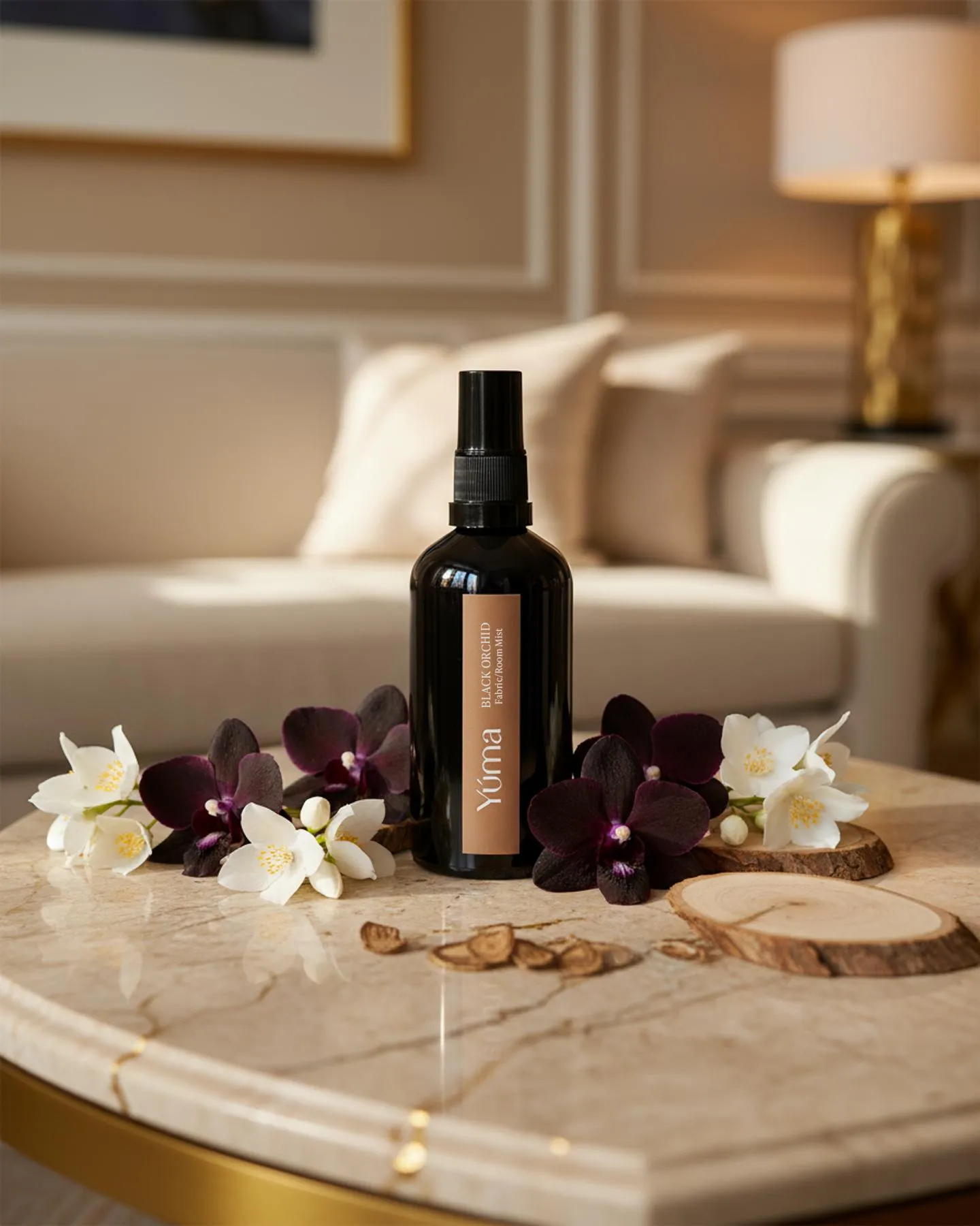 Μαύρο μπουκάλι Fabric Mist Black Orchid της YUMA ανάμεσα σε σκούρες ορχιδέες και λευκά άνθη.