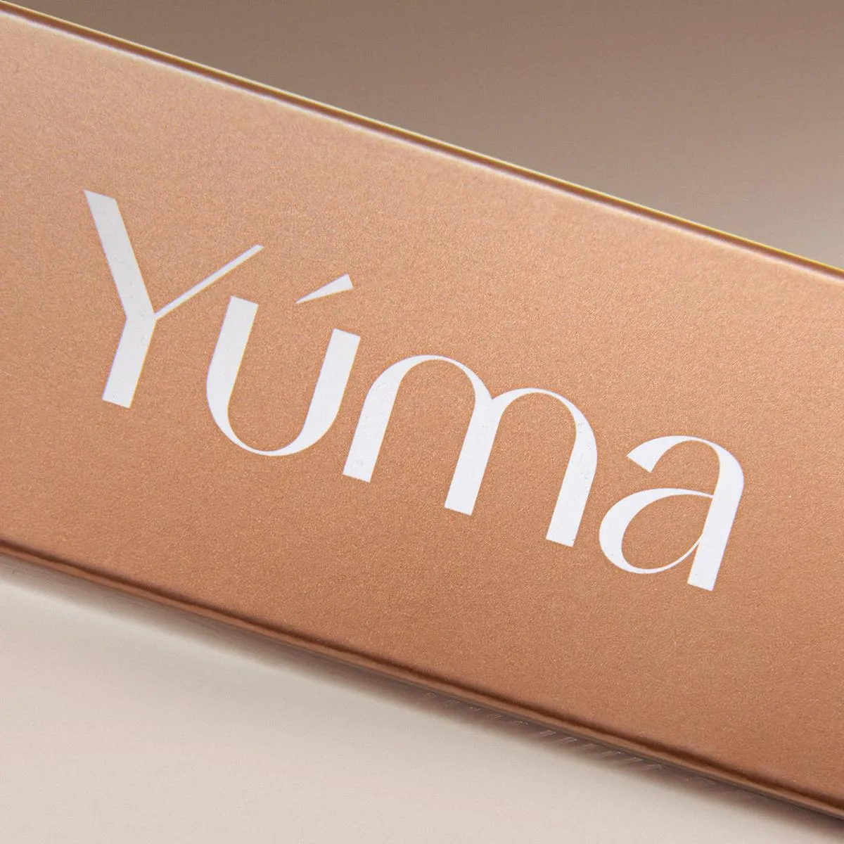Κοντινή λήψη της χρυσής συσκευασίας Luxe Philoxenia της YUMA με το λογότυπο σε λευκό χρώμα.