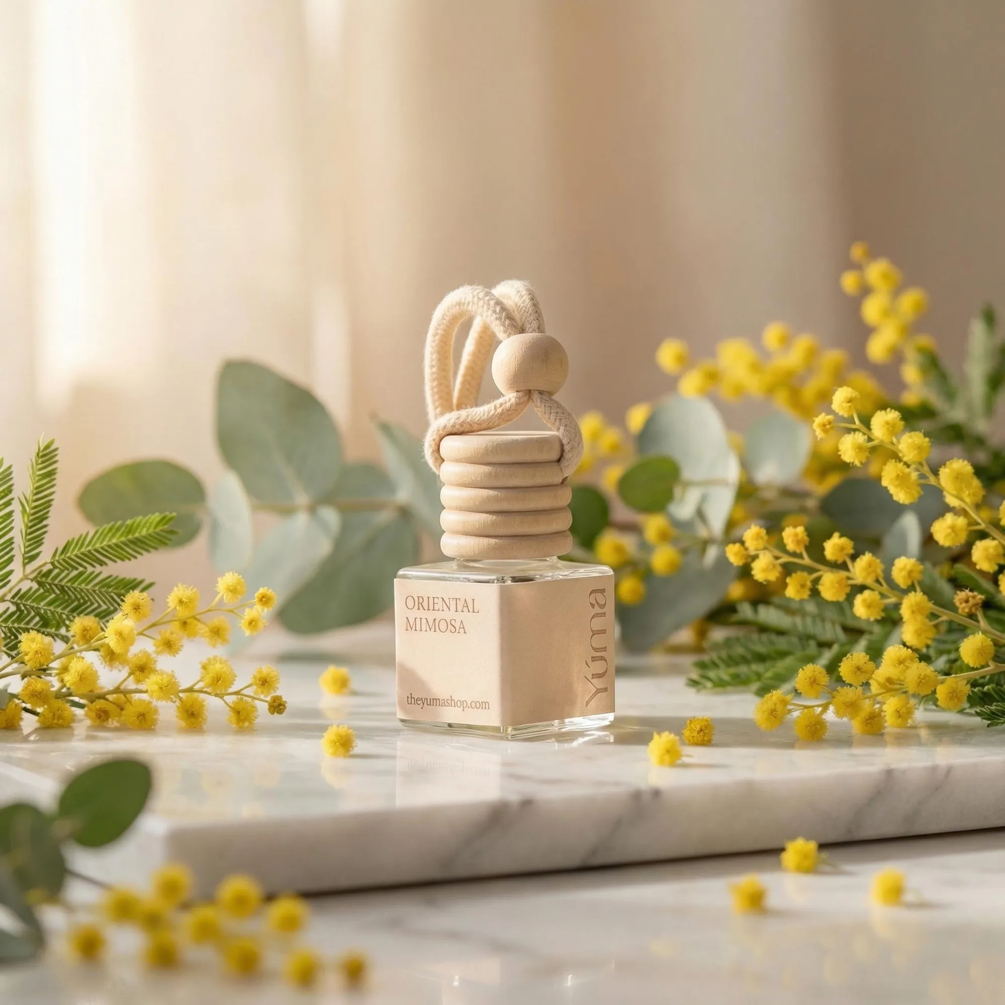 Car Diffuser της YUMA με άρωμα Oriental Mimosa πάνω σε μάρμαρο με κίτρινα άνθη μιμόζας.