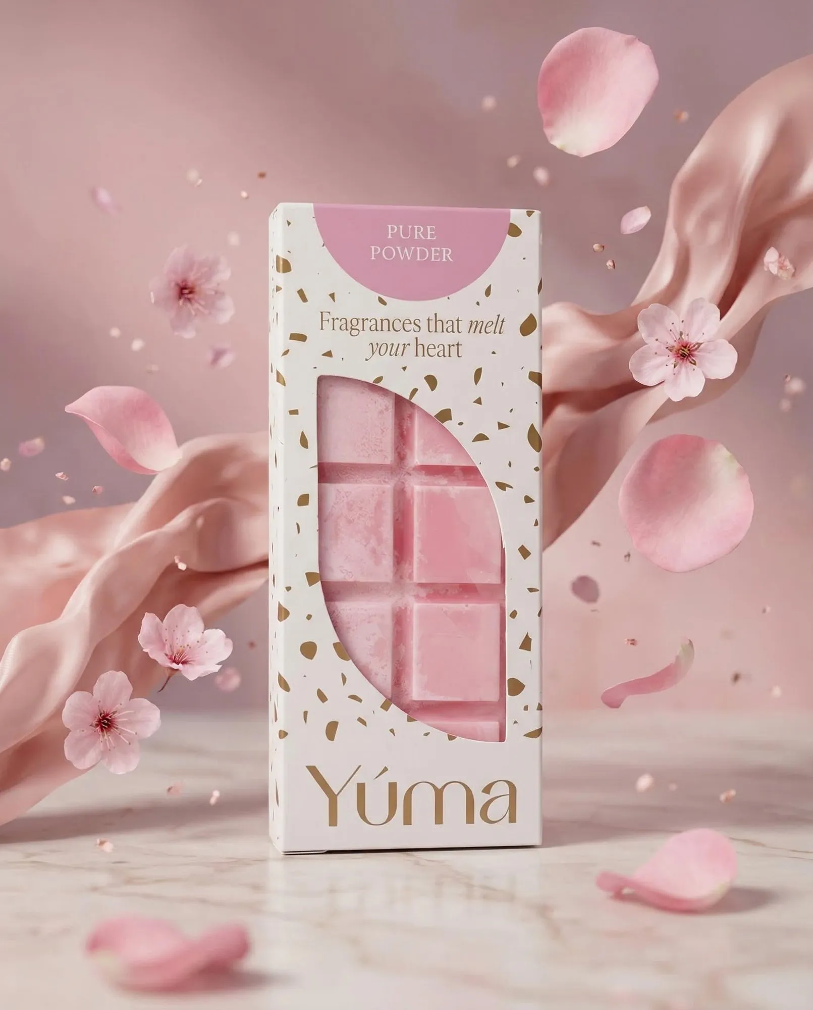 Ροζ wax melts Pure Powder της YUMA σε λευκή συσκευασία ανάμεσα σε πέταλα και άνθη κερασιάς.