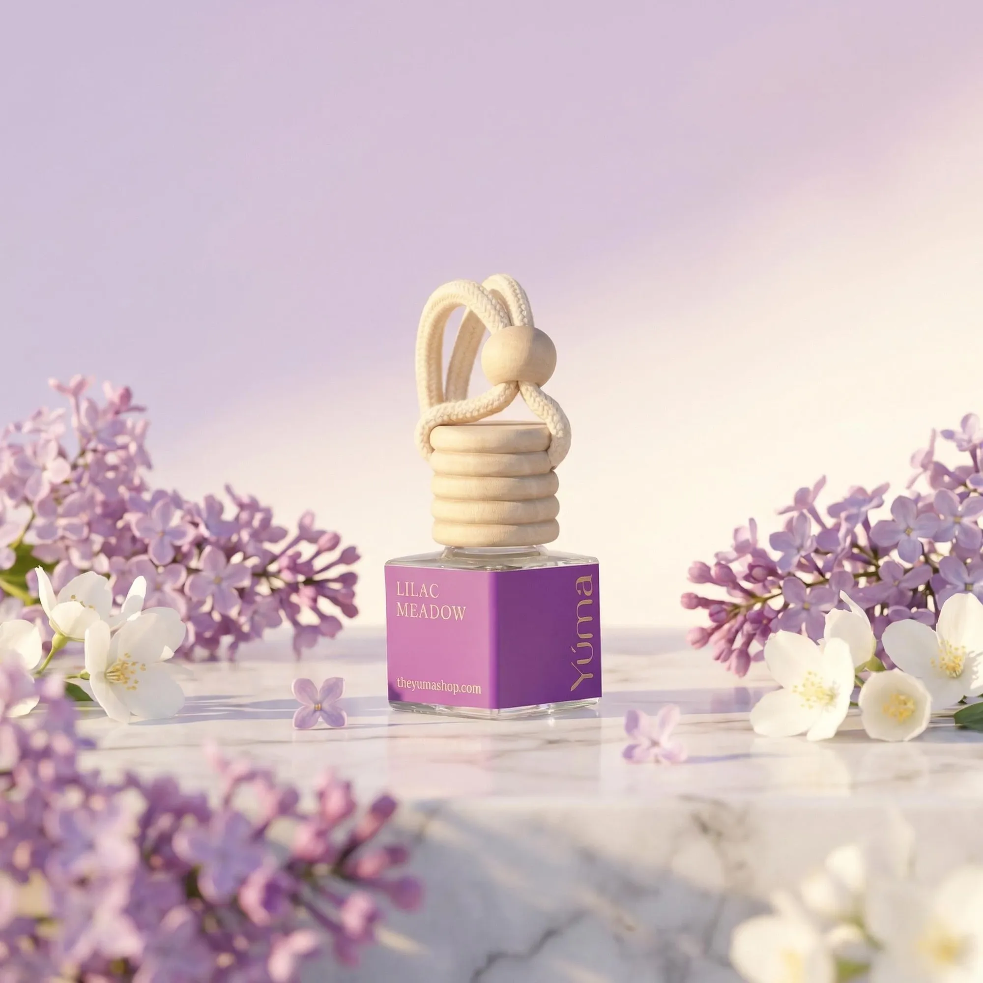 Μωβ Car Diffuser Lilac Meadow της YUMA σε μαρμάρινη επιφάνεια ανάμεσα σε πασχαλιές και λευκά άνθη.