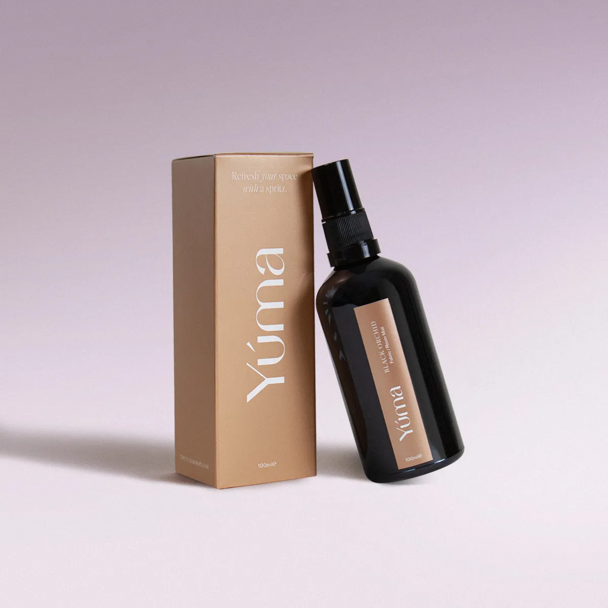 Black Orchid Fabric/Room Mist Μαύρο μπουκάλι fabric mist Black Orchid της YUMA δίπλα στην μπεζ χάρτινη συσκευασία του.