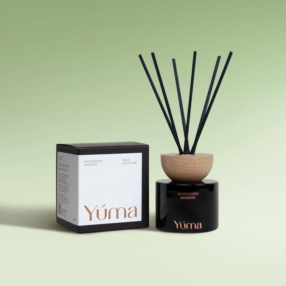 Hesperides Jasmine Reed Diffuser Reed diffuser Hesperides Jasmine της YUMA σε μαύρο γυάλινο δοχείο δίπλα στη συσκευασία του.